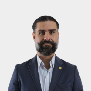 Professor Carlos Muvdi Nova of the School of Chemical Engineering is presented to the general public and the educational community. The photo was taken in close-up, with a white background, and the professor is positioned in the center.