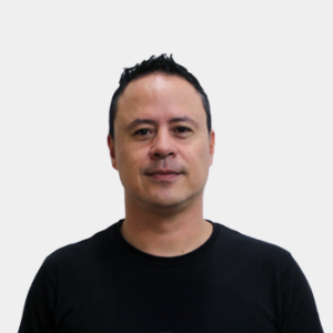The professor of the School of Arts and Music, Jhon Eduard Ciro Gómez, is presented to the general public and the educational community. The photo was taken in close-up, on a white background, and the professor is positioned in the center.