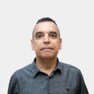 La foto fue tomada en primer plano, fondo blanco y el profesor Jhon Jairo Caceres está situado en el centro.